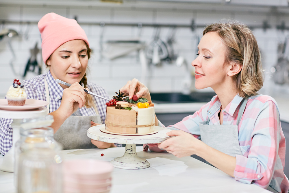 professional pastry chef shows college-aged student how to make a cake