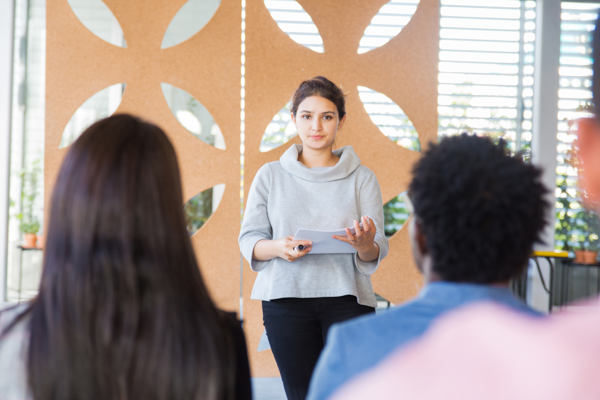 Professional female presents information to small audience 