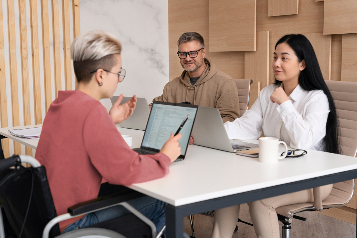 young professional in wheelchair meets with two colleagues at table 