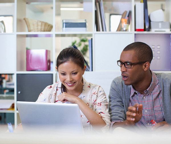 two professionals look at laptop screen together in office