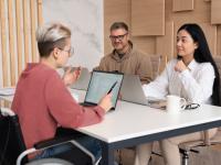 young professional in wheelchair meets with two colleagues at table