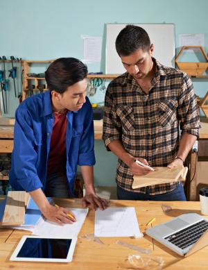 professional worker explaining carpentry basics to his newcomer colleague 
