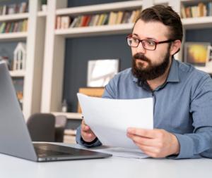 professional male watches Module 1 while holding a lesson printout in his hand