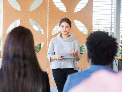 Professional female presents information to small audience