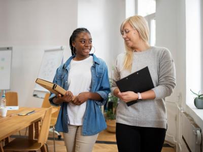 professional female walks and talks to younger female in office