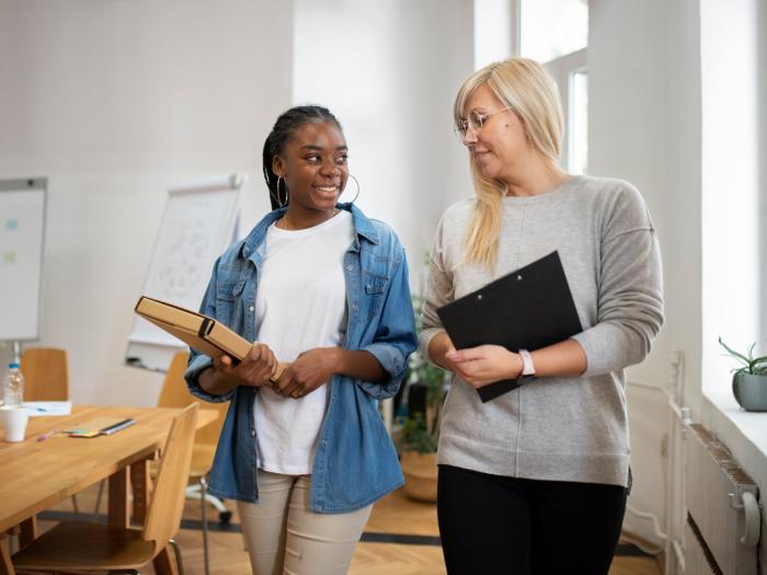 professional female walks and talks to younger female in office