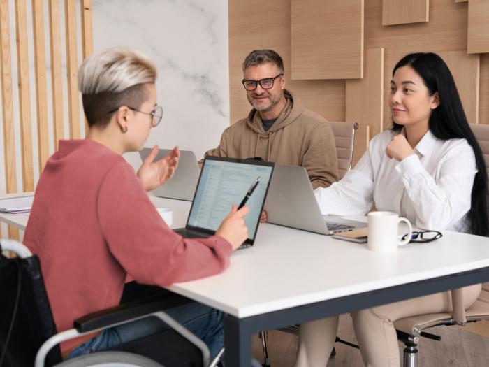 young professional in wheelchair meets with two colleagues at table