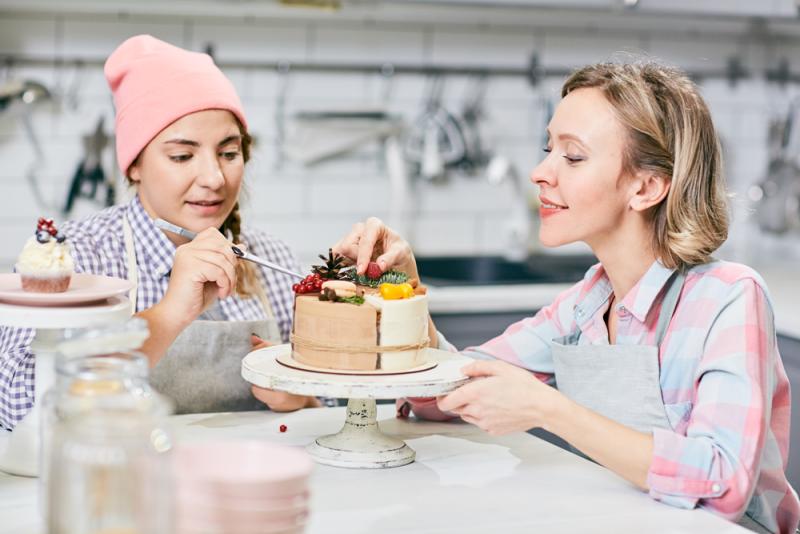 professional pastry chef shows college-aged student how to make a cake 